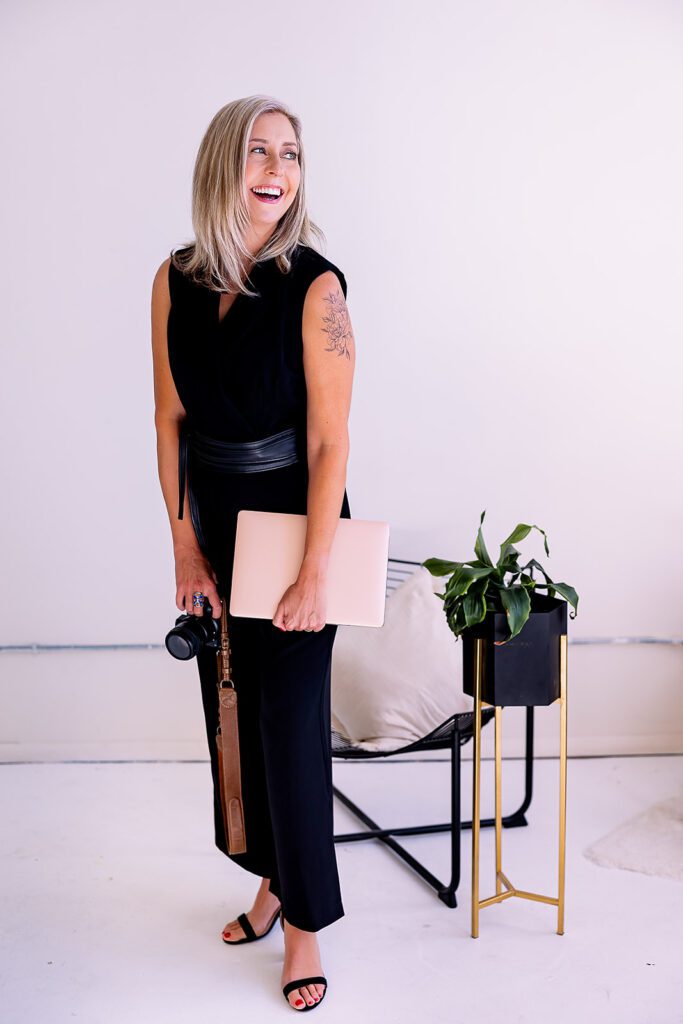 woman holding camera and laptop laughing