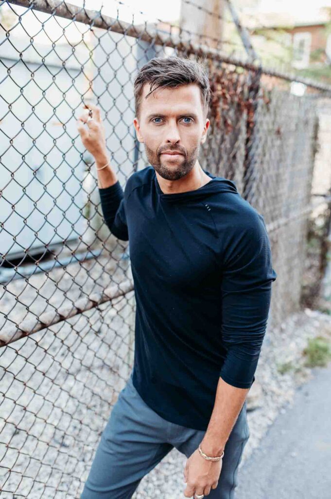 Man standing next to chain link fence looking at camera